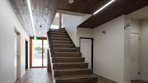 A modern interior with a wooden staircase, a visible laundry room, and a door marked "TOILET". - Lodges Daikoku (Toyama)