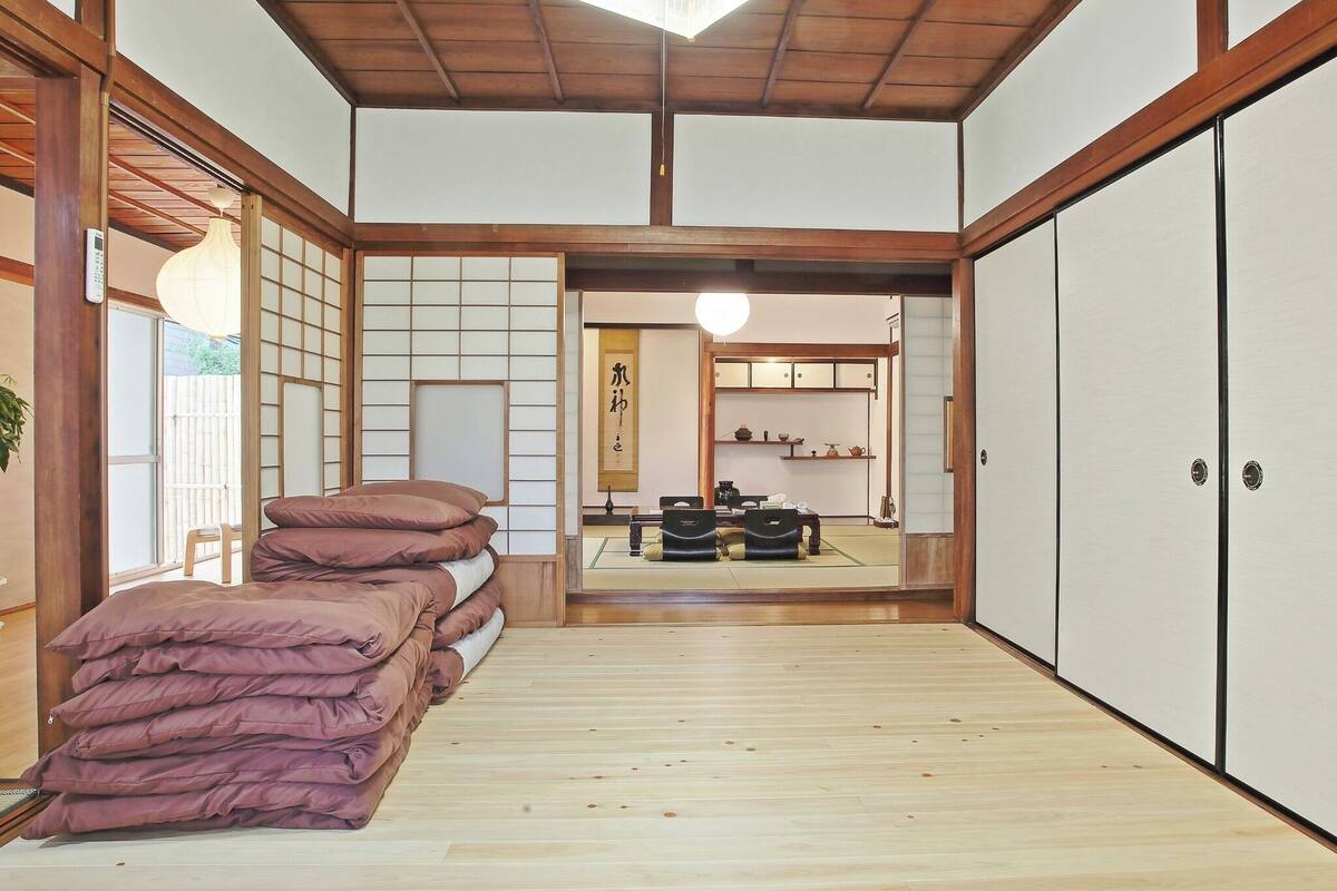 A traditional Japanese-style room with tatami flooring, a low wooden ceiling, and sliding doors.