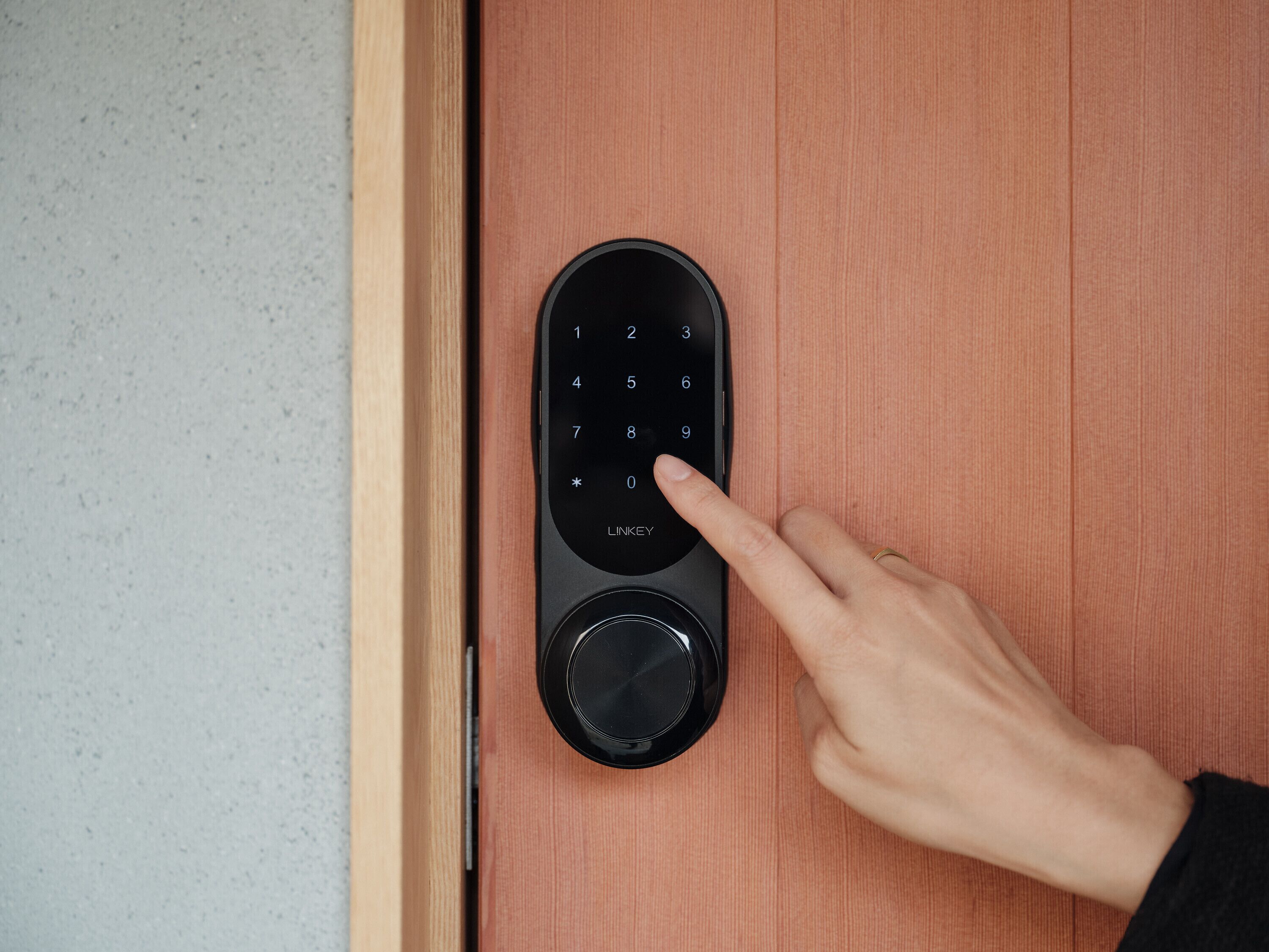 A person using a keypad lock on a wooden door.