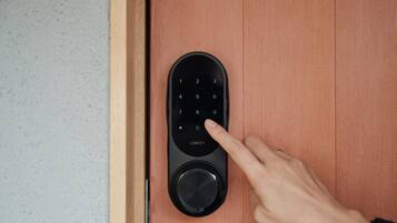A person using a keypad lock on a wooden door.