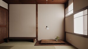 Een minimalistische kamer in Japanse stijl met tatami vloeren, een lage houten bank, een hanglamp en een kleine potplant.