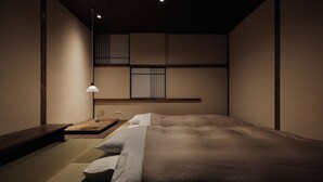 Een minimalistische slaapkamer met een groot bed, een nachtkastje en een hanglamp.