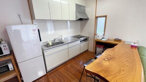 Una cocina compacta con alacenas blancas, un lavamanos de acero inoxidable, un microondas y un tostador.
