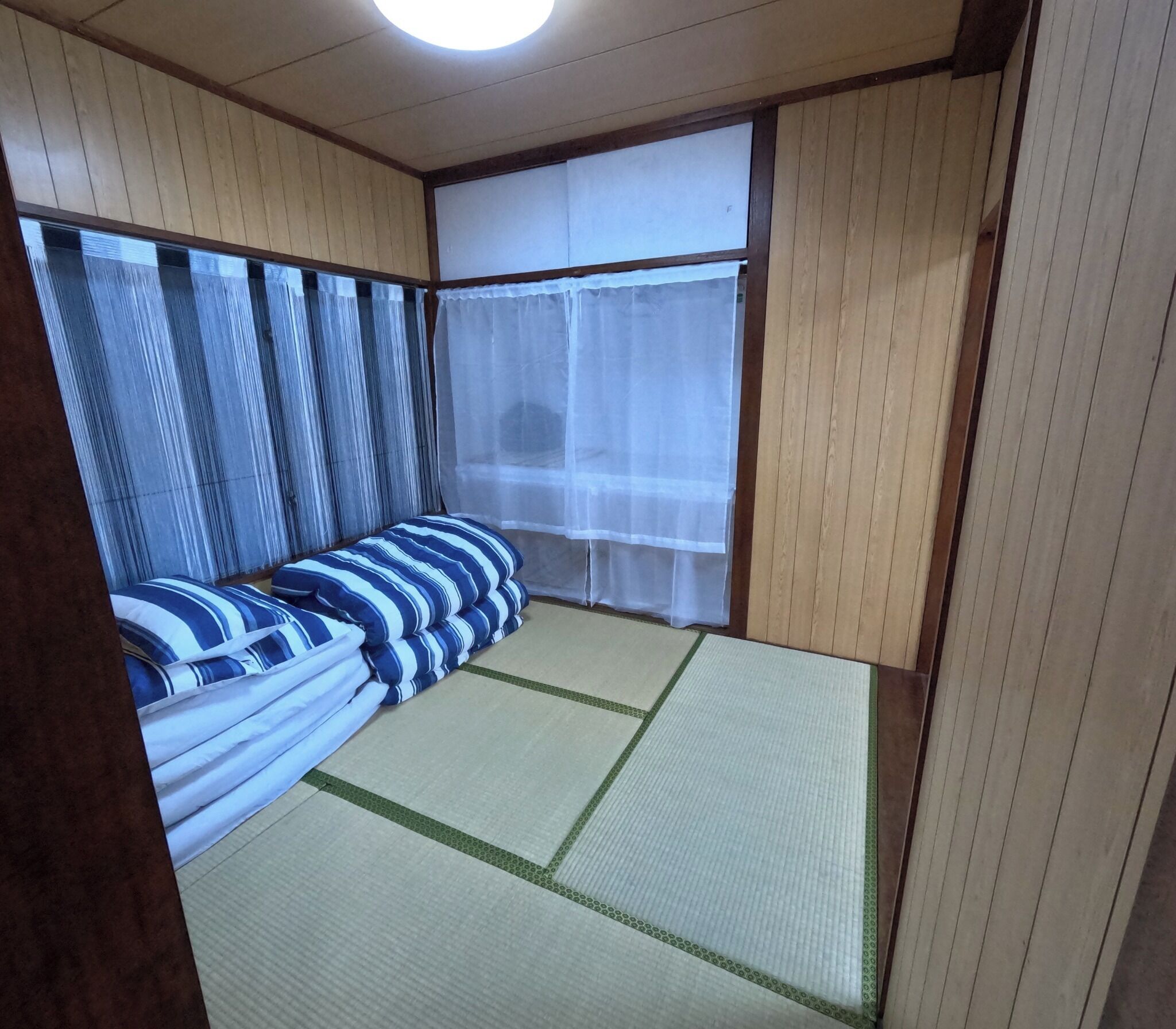 A traditional Japanese-style room with tatami flooring, a futon bed, and shoji screens.