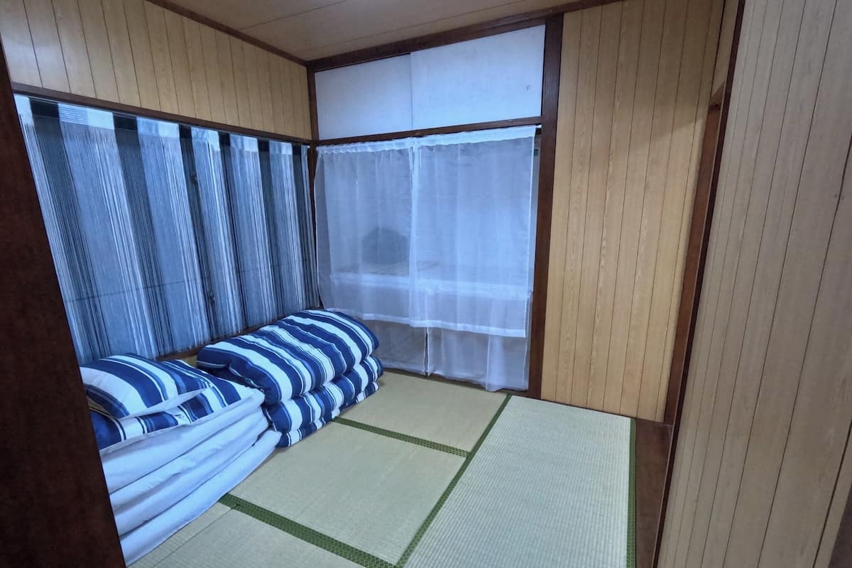 A traditional Japanese-style room with tatami flooring, a futon bed, and shoji screens.