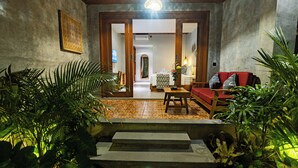 Un vestíbulo de hotel con una escalera que conduce a una habitación, un sofá rojo, una mesa de madera y plantas en macetas.