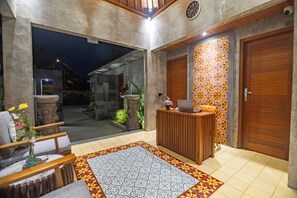 A reception area with a desk, chairs, a patterned rug, and a wooden door. - The Dura Ubud (Ubud)
