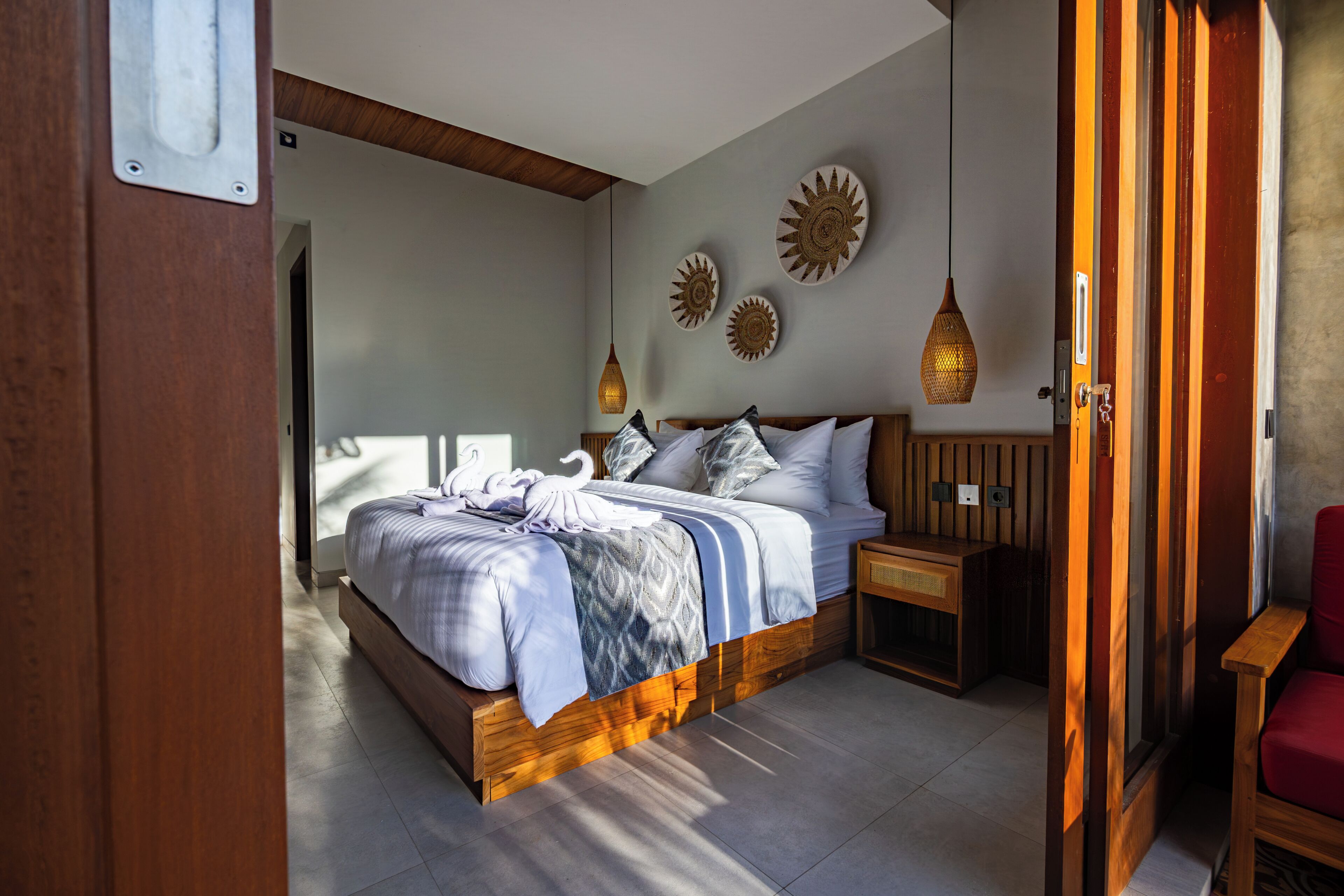 A bedroom with a bed, bedside tables, a red chair, and decorative wall art.