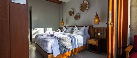 A bedroom with a bed, bedside tables, a red chair, and decorative wall art.