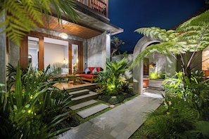 A modern house with a patio, outdoor seating, and lush greenery.