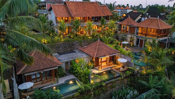 Un resort con varias construcciones, piscina y abundante vegetación.