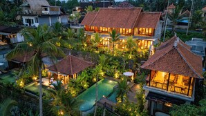 Un resort con varias edificaciones, una piscina y abundante vegetación.