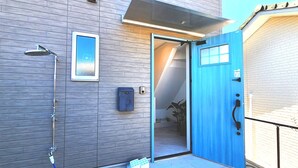 Een moderne badkamer met een douche, een blauwe deur en een raam.