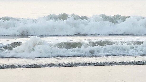 Een strand met golven die op de kust breken.