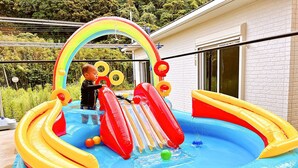 Une piscine gonflable avec des toboggans et un arc-en-ciel.