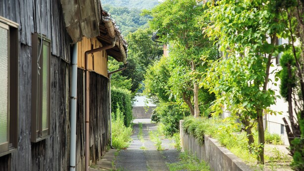 A narrow alleyway flanked by traditional wooden buildings with a stone pathway. - Destiny Seaside Village (Sakaiminato)