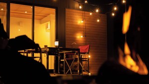 An outdoor seating area with a table, chairs, and string lights.