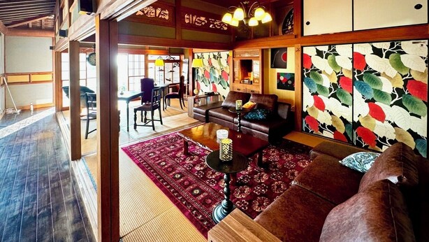 Una habitación tradicional japonesa con suelo de tatami, techo de madera bajo y puerta corredera.