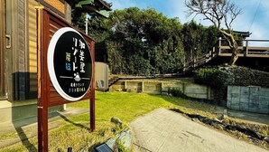 Un edificio japonés tradicional con un letrero, un sendero de piedra y una valla de madera.