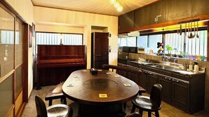 Una cocina moderna con una isla central, un área de comedor con una mesa redonda y sillas, y un piano al fondo.