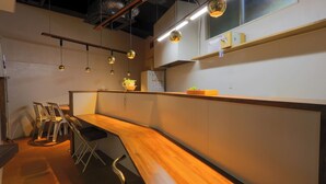 A modern kitchen with a wooden counter, hanging pendant lights, and a refrigerator.