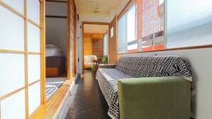 A traditional Japanese room with tatami flooring, a low wooden bed, a sofa, and sliding doors.