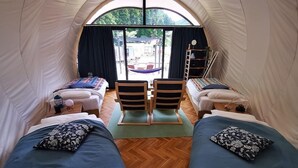 A tent with two beds, a table, chairs, and a view of the outside.