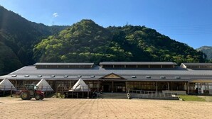 A traditional Japanese building with a tiled roof, a wooden structure with a sloped roof, and a small porch area.