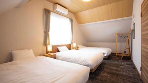A room with two beds, a wooden ceiling, an air conditioning unit, a window with curtains, a wooden ladder, and a carpeted floor.