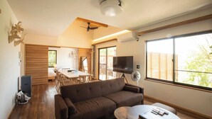 A modern living room with a brown sofa, a dining table, and a TV.