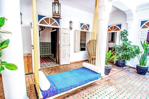 A traditional Moroccan room with a patterned floor, a bed with a blue and red bedspread, and potted plants. - RIAD EN PRIVATISATION - Heated Rooftop Pool - MARRAKECH MEDINA (Marrakesh)