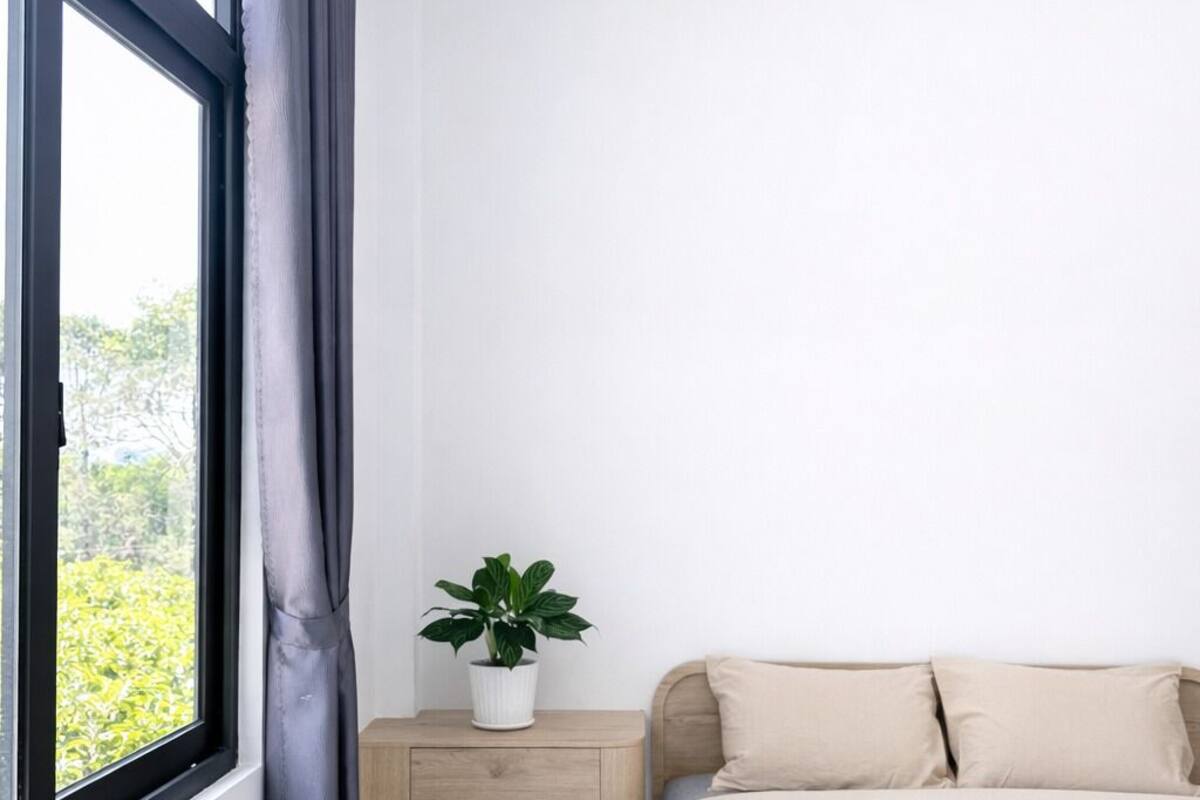 Un dormitorio con cama, escritorio, silla y ventana con cortinas.