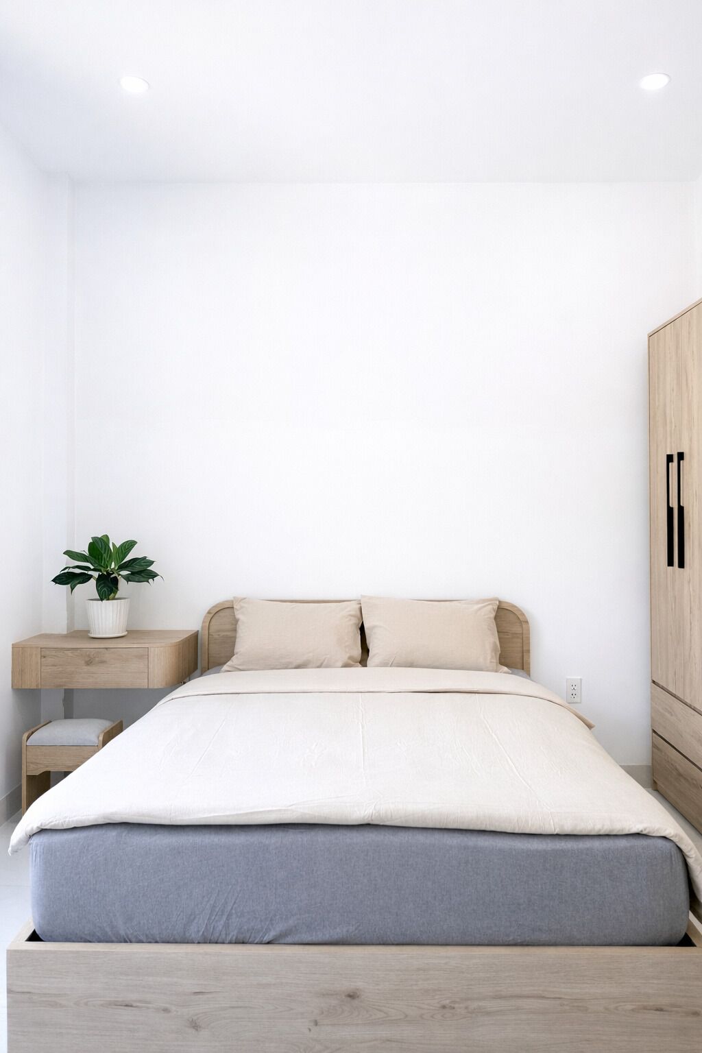 Et minimalistisk soveværelse med seng, natbord og garderobe.