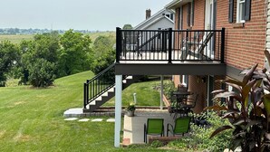 A house with a covered patio, outdoor seating, and a view of the countryside. - Hilltop Guesthouse - in Intercourse on Beacon Hill, 4-Bedroom House (Ronks)