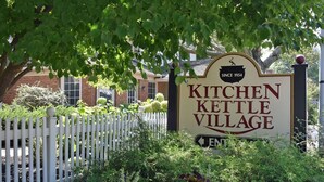 A sign for Kitchen Kettle Village with a white picket fence and greenery in the background. - Hilltop Guesthouse - in Intercourse on Beacon Hill, 4-Bedroom House (Ronks)