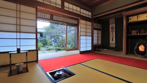 Une pièce de style japonais traditionnel, avec un sol recouvert de tatamis, des portes coulissantes et une vue sur un jardin.