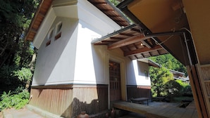 Un bâtiment à l’extérieur blanc, avec une porte en bois et un porche abrité.