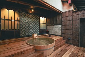 A traditional Japanese onsen with a wooden hot tub, wooden steps, and a tiled wall with a geometric pattern. - The Timeless Hotel Loof Yunoie (Yachiyo)