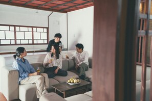 Un grupo de personas sentadas en un sofá en una habitación con un ventanal grande y techo de madera.