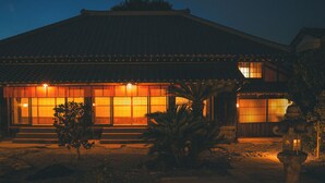 A traditional building with a tiled roof and large windows, surrounded by a garden with a stone lantern and a palm tree. - The Timeless Hotel Loof Yunoie (Yachiyo)