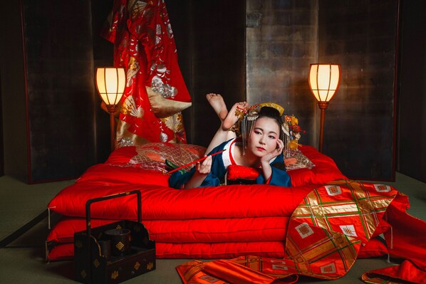 A traditional room with a large bed, two wall-mounted lamps, and a decorative red and gold patterned curtain.