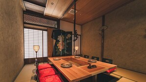 A traditional Japanese-style room with tatami flooring, a low wooden table, and red cushions. - The Timeless Hotel Loof Yunoie (Yachiyo)