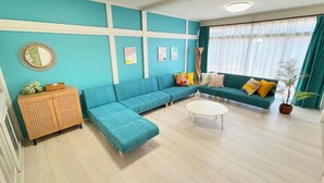 A modern living room with teal walls, a sectional sofa, a round coffee table, and a wooden cabinet.