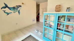 A room with a light wooden floor, a blue cabinet with glass doors, and a wall mural of whales.