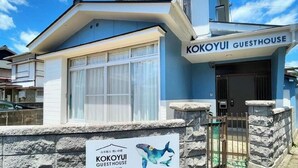 A guesthouse named KOKOYUI with a stone wall entrance and a sign featuring a whale illustration.