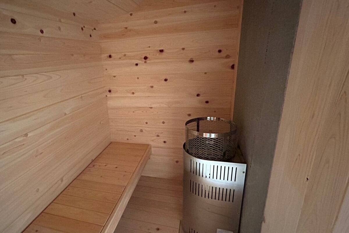 A wooden sauna room with a bench and a metal heater.