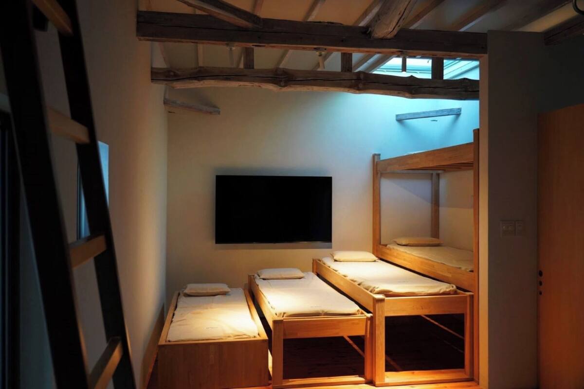 A room with bunk beds, a flat-screen TV mounted on the wall, and a skylight above.