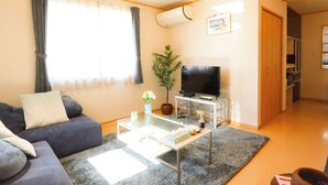 A living room with a sofa, coffee table, TV, and a plant. - K-style Resort (Yugawara)