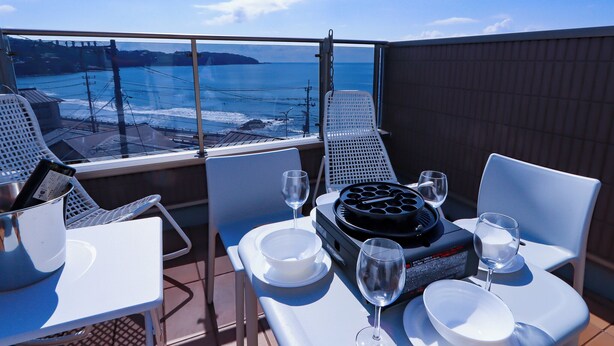 A balcony with a table set for two, overlooking a coastal view. - K-style Resort (Yugawara)
