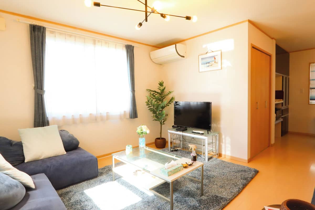 Una sala de estar con sofá, mesa de centro, televisor y una planta.
